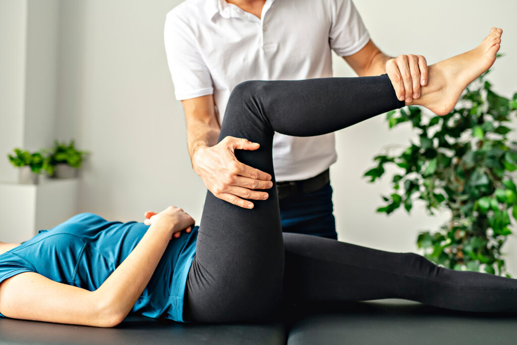Un fisioterapista professionista che effettua un trattamento alla gamba di una paziente in uno studio luminoso, sottolineando l'importanza della riabilitazione e della terapia fisica.
