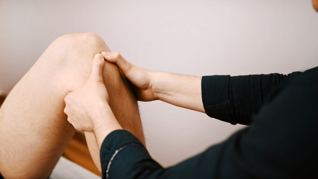 Fisioterapista in azione mentre esegue un trattamento manuale su un ginocchio del paziente, evidenziando la qualità del servizio che è uno dei fattori che determina i costi di un ciclo di fisioterapia.