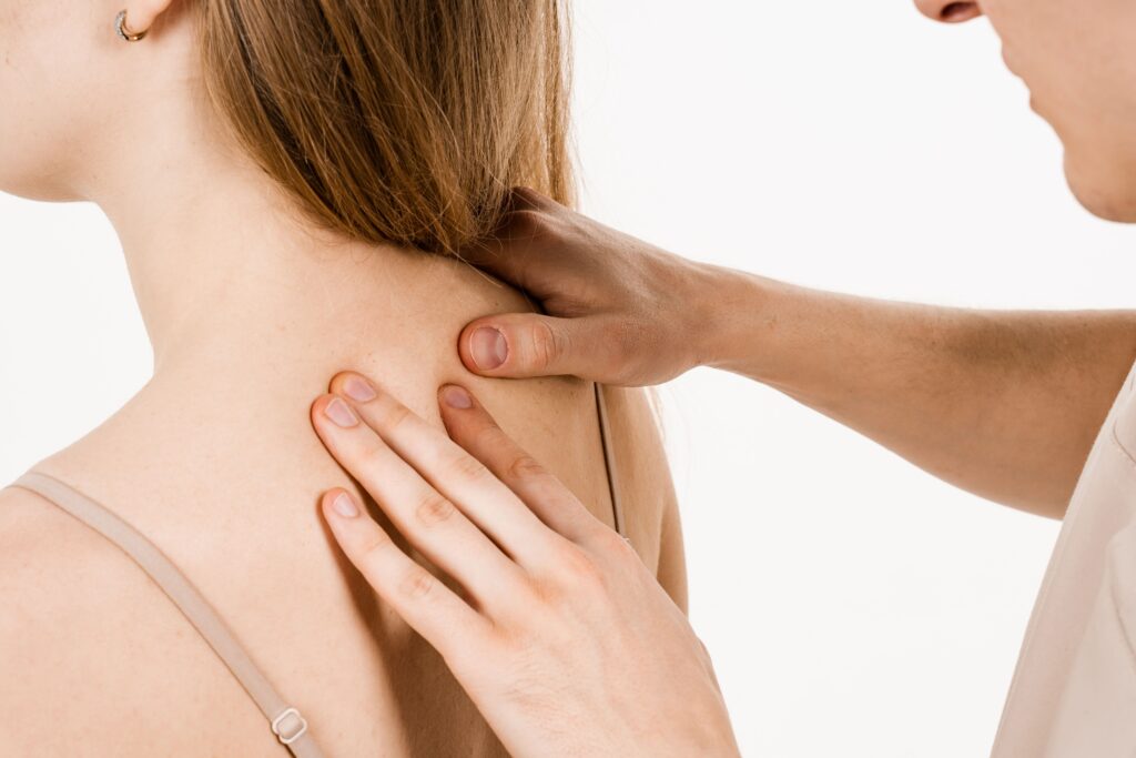 Un fisioterapista sta eseguendo un trattamento manuale sulla parte alta della schiena di una paziente. Le mani del terapista sono posizionate con precisione sui muscoli vicino alla scapola, una zona comune per il dolore nella parte alta della schiena. La paziente appare rilassata durante l'intervento. L'immagine mostra una tipica sessione di fisioterapia mirata ad alleviare il mal di schiena alto.