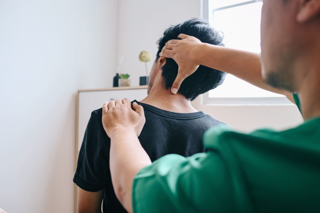 Un fisioterapista sta effettuando una valutazione palpatoria sulla nuca di un paziente per identificare i possibili tipi di mal di testa. La terapia manuale viene utilizzata come metodo di diagnosi e trattamento per i disturbi associati al mal di testa in un ambiente clinico luminoso e tranquillo.